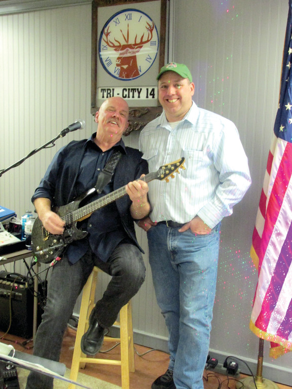 ASSIST WITH AUCTION: Guitarist-entertainer Cliff Myers (left) and Ed Egan, director of development at the Trudeau Memorial Center, who helped coordinate a huge auction and raffle, enjoy a lighter moment during the celebration of Lenn Murphy’s life last Saturday.