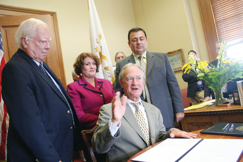 STRIKING OUT THE MASTER LEVER: Joining Governor Chafee at the bill signing ceremony were, behind governor from left, are Senator Bates, Rep. Mia Ackerman (D-Dist. 45, Cumberland, Lincoln), who co-sponsored the House bill, and Rep. Shekarchi.