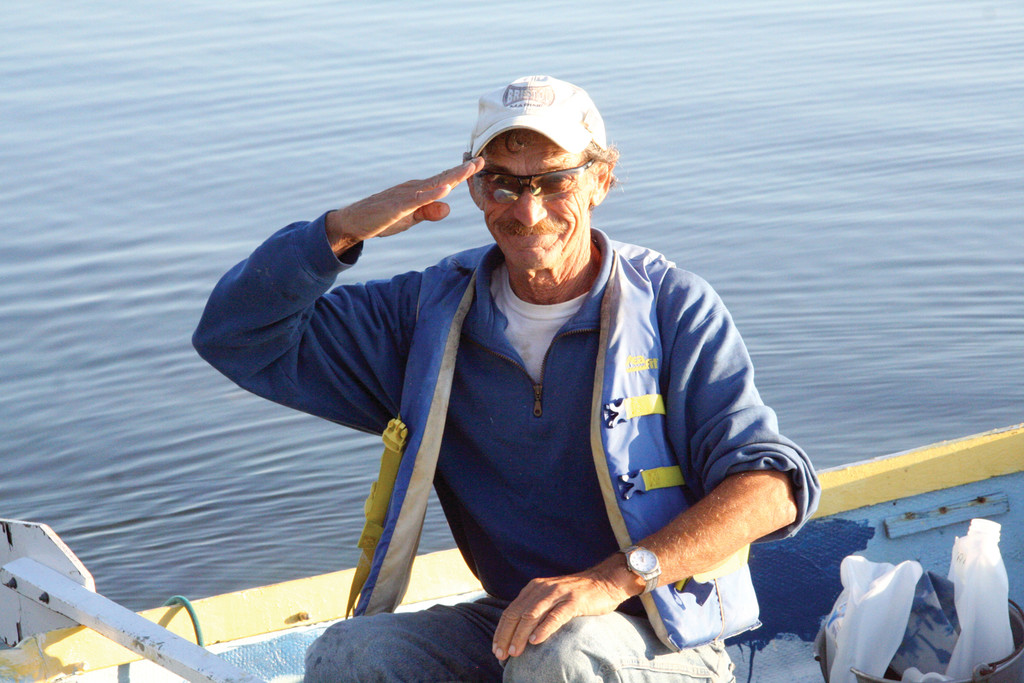 CLASSIC 
CAPTAIN FREDY: Captain Fredy Silva salutes as he paddles ashore from his sailboat moored off Conimicut late this July.