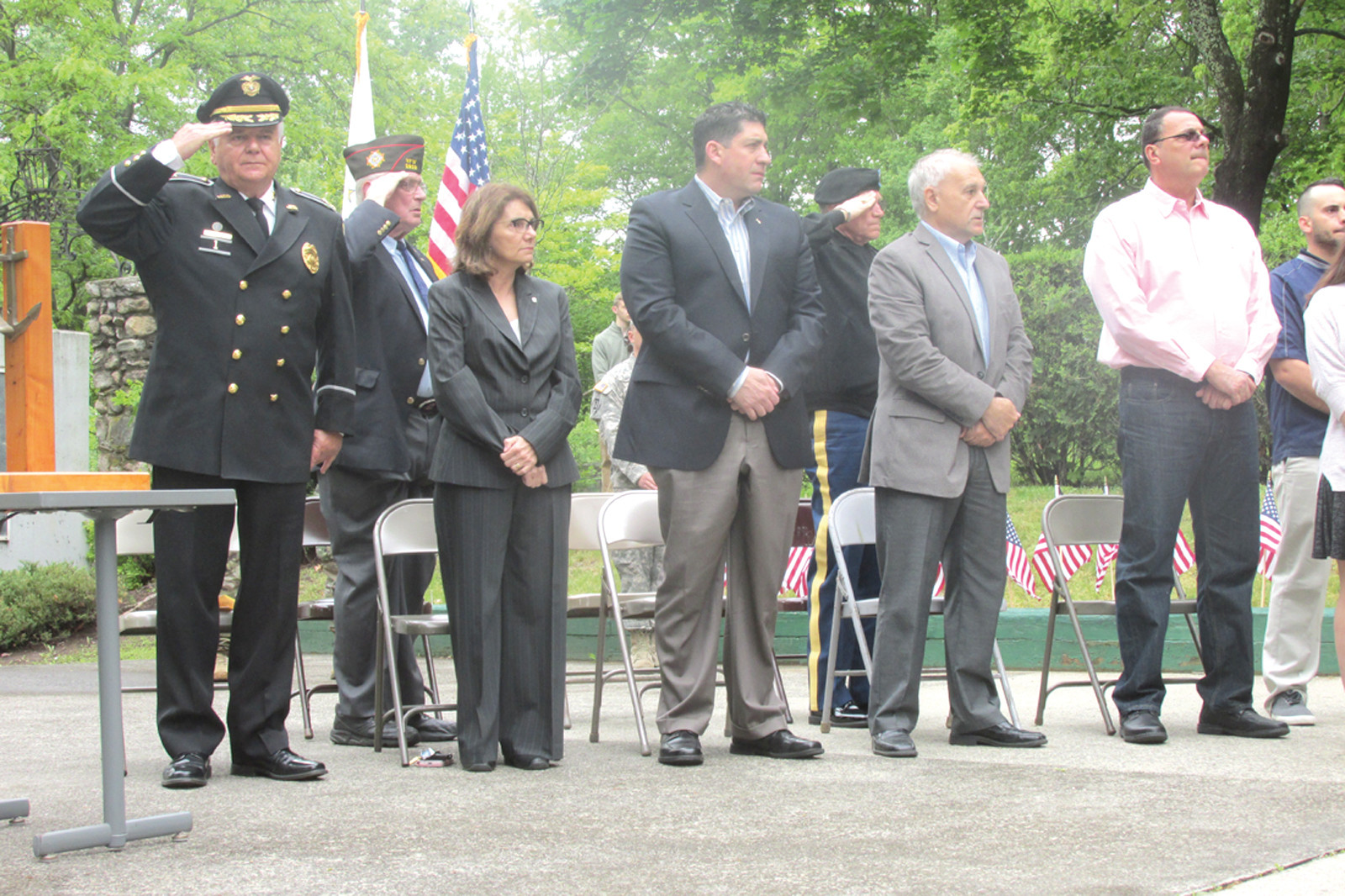 SPECIAL SALUTE: As Johnston Police Chief Richard S. Tamburini salutes the flag during the National Anthem, town officials stand  amid military personnel and impressive monuments of deceased Johnston veterans who helped preserve the nation’s freedom.