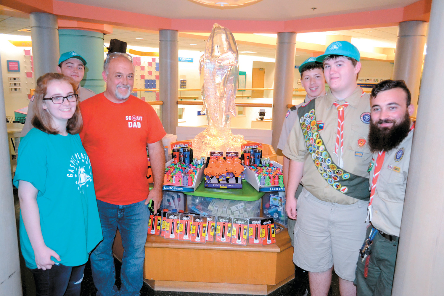 GUIDING LIGHTS: Eion Daniels (right middle) and his fellow Scouts Mitchell Carvalho (left middle), Ben McQuade (right, rear) and David Tibbitts (right front), his sister Mollee and father Tom prepare the flashlights for Hasbro staff on Thursday afternoon.
