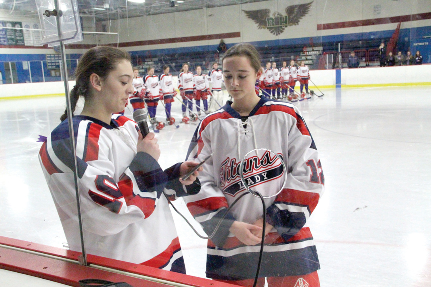 IN TRIBUTE TO GIANNA: Co-captains of the Lady Titans Hockey Tea Shannon McCamish and Elise Saccoccia read tributes to Gianna in a ceremony preceding their game with Mount St. Charles.