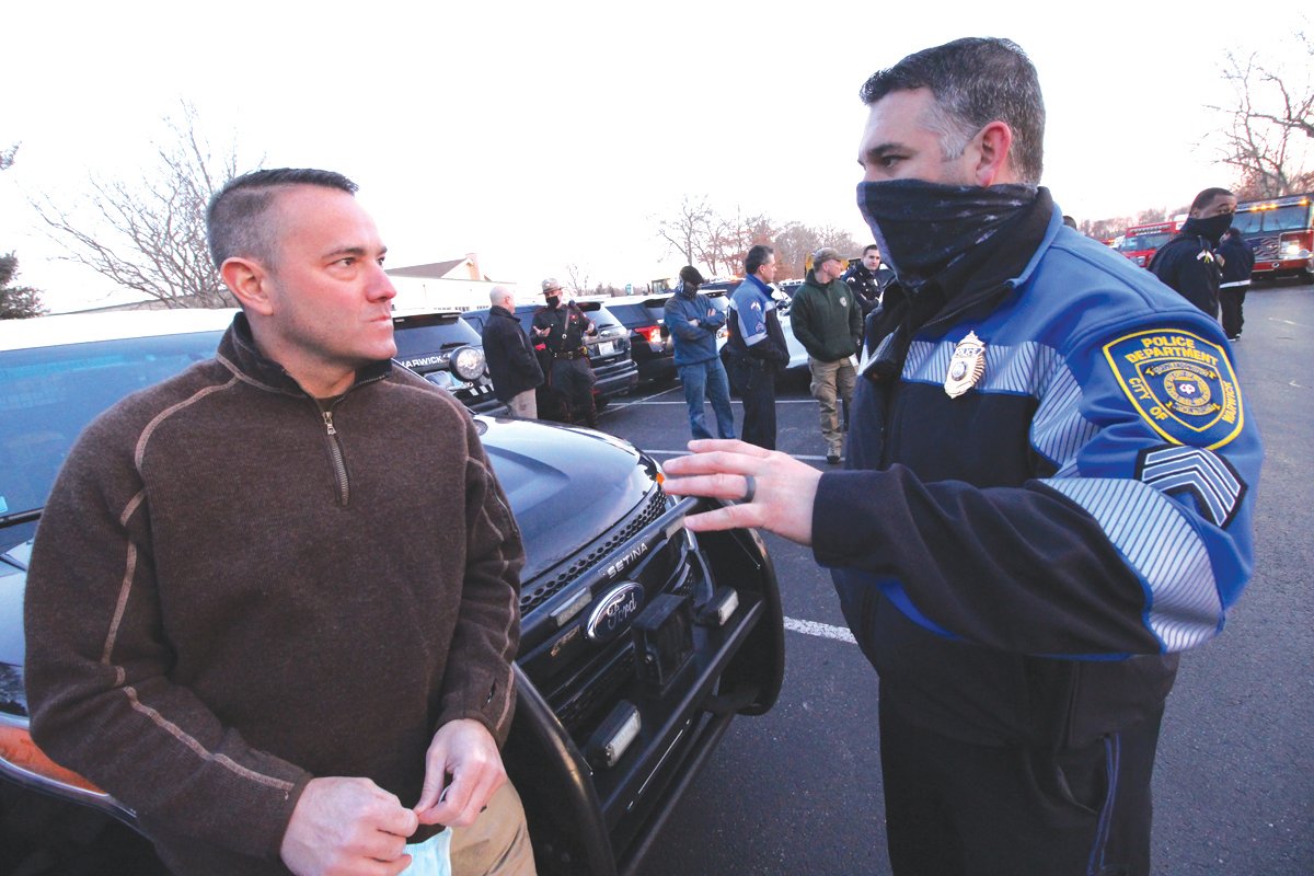 PARADE PLANNER: Sgt. Matthew Higgins, left, who rallied first responders for Monday’s parade talks with Col. Brad Connor as police cruisers, fire apparatus and even front end loaders (vehicles with flashing lights) assembled at the Hendricken parking lot.