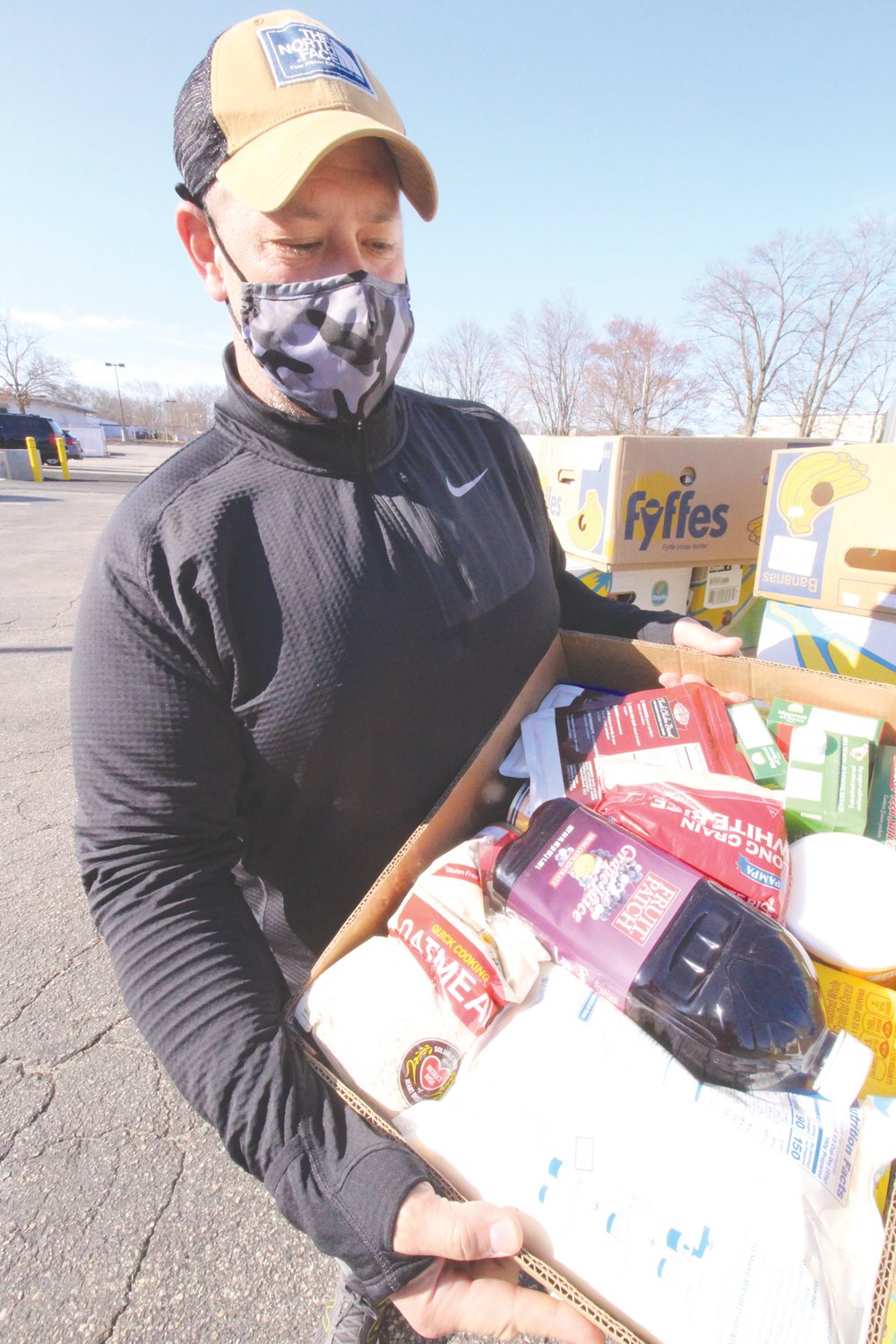 READY TO ASSIST : Paul Salera, executive director of Westbay Community Action displays the contents of one of the boxes of food distributed to those showing up to Saturday’s event. About 230 boxes were distributed.