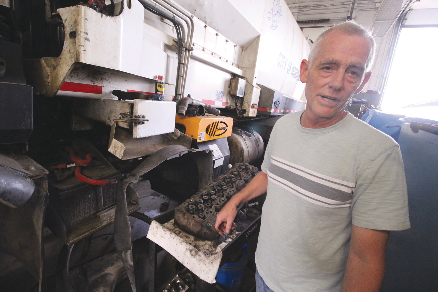 IN NEED OF AN ENGINE: James Vangyzen beside one of the sanitation trucks that is currently out of commission and in the city garage. City mechanics are rebuilding the engine, estimated to cost $8,000 in parts. A rebuilt engine off the shelf would cost about $30,000.