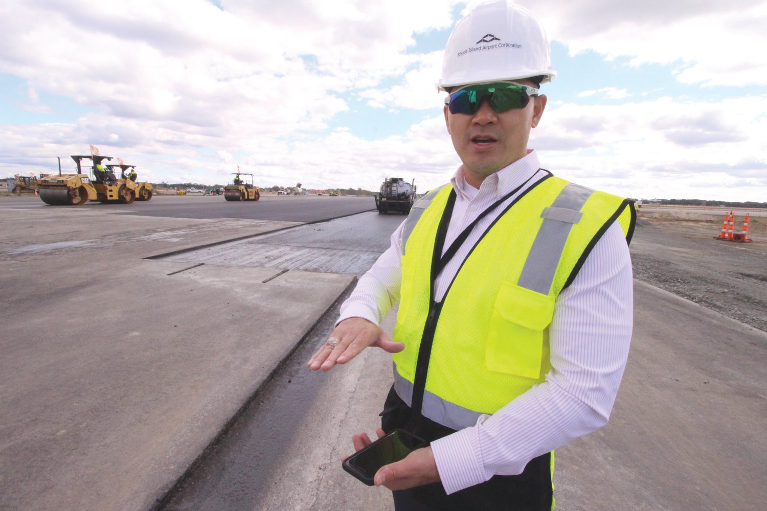 IT’S THAT THICK: Duc Nguyen, chief infrastructure officer at the Rhode Island Airport Corporation, beside a section of Runway 16-34 set to receive another layer of asphalt.