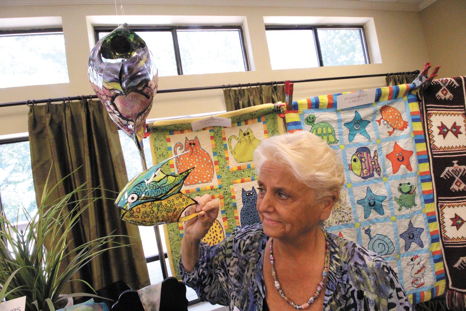 FLYING FISH:  Holly Desrosiers with the colorful fish she created from plastic soda bottles.