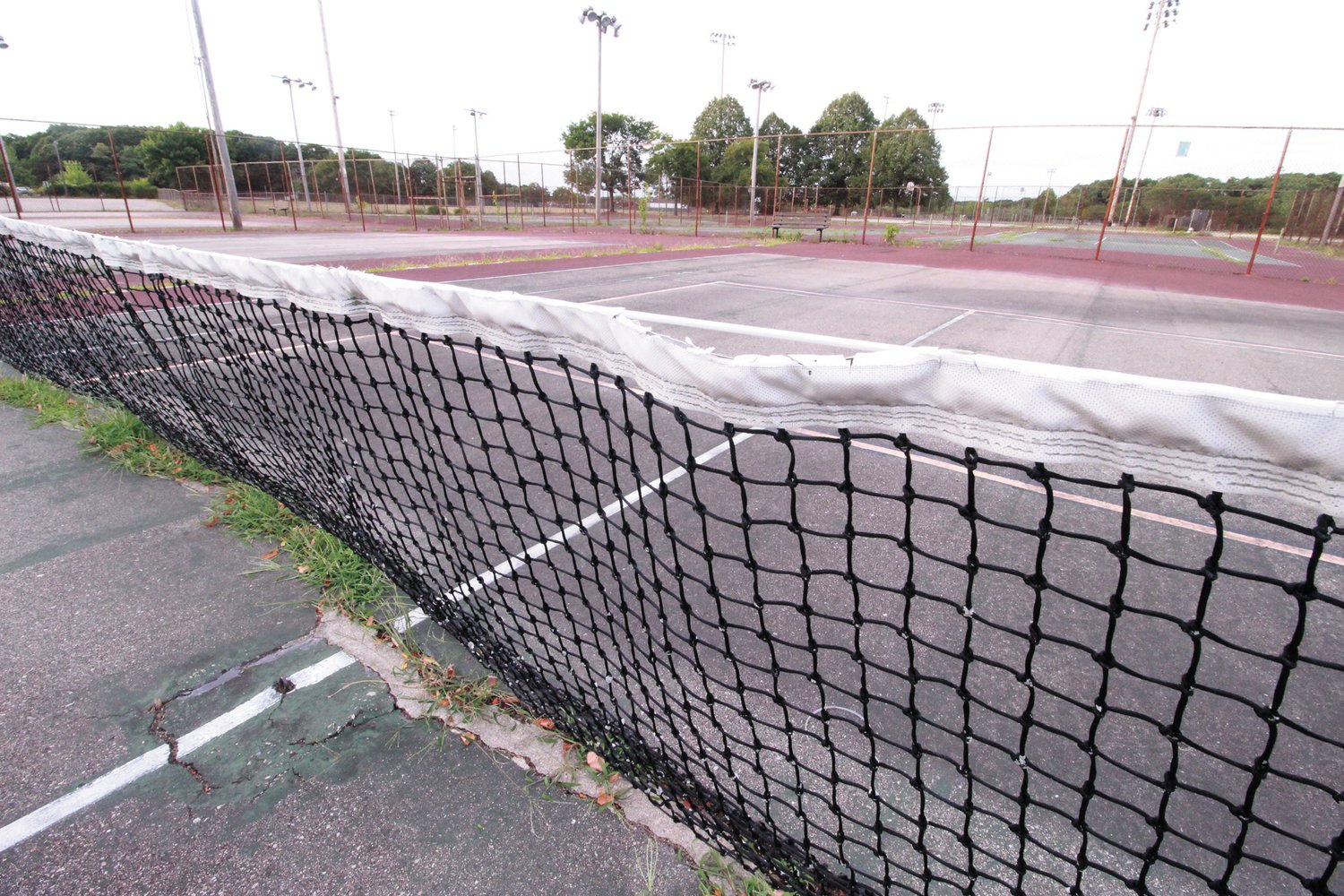 WEEDY COURTS: The tennis and basketball courts at Mickey Stevens Sports Complex are showing their age. When this picture was taken Sunday afternoon, no one was to be found except for a man shooting baskets. “I do it to clear my head,” he said. (Warwick Beacon photo)