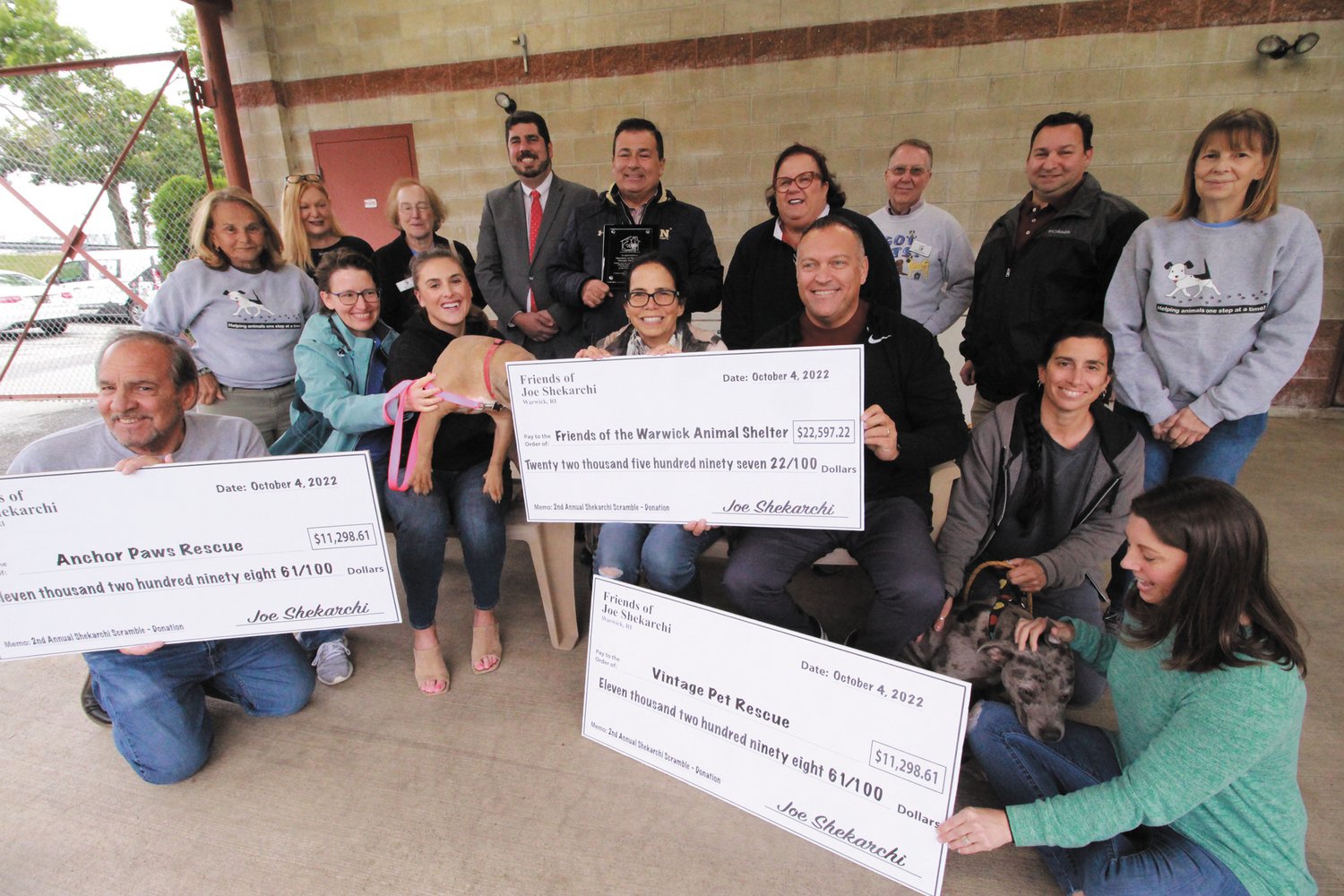 PHOTO OP WITH CHECKS AND DOGS: Representatives of three humane organizations and legislators were joined by Speaker K. Joseph Shekarchi  Tuesday afternoon at the Warwick Animal Shelter. Shekarchi presented proceeds of the his golf scramble held in August to the organizations (Warwick Beacon photo)