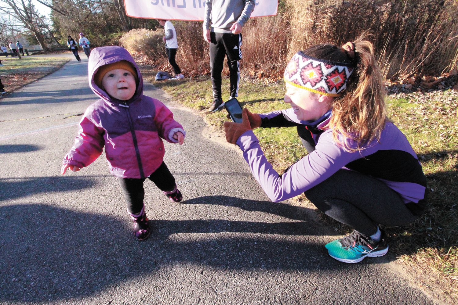 ACROSS THE FINISH LINE: Nineteen-month old Everly Speed is encouraged by her mother Kayla as she steps across the finish.