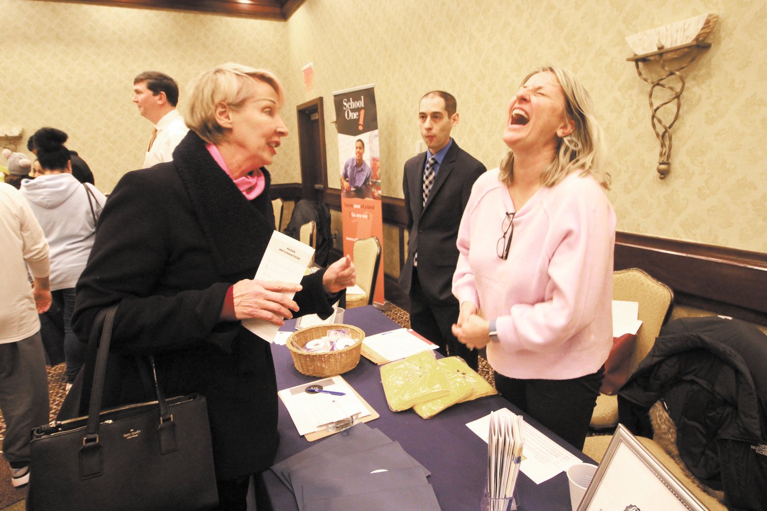 SHARING A LAUGH: Megan Reilly, a member of the group planning to open the state’s newest Catholic high school – Chesterton Academy on Jefferson Boulevard in Warwick, shares a laugh with one of those attending Sunday’s school choice fair. The academy that has a core group of twelve 9th and 10th graders, plans to open this fall.