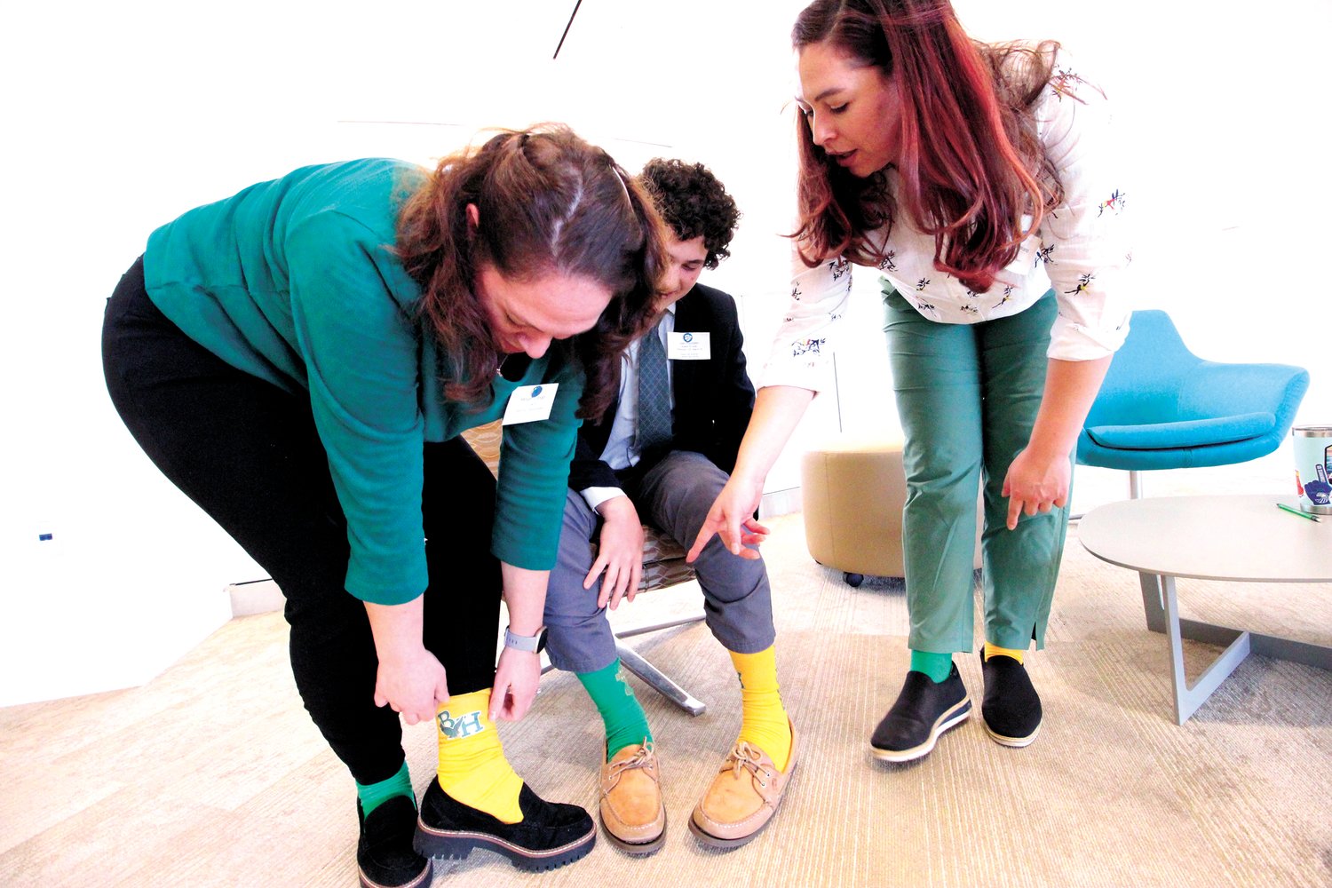 A FOOT UP ON THE REST: Hendricken team members and their coaches wore one green and one yellow sock to match the school’s colors for the competition. Here Coaches Meghan Longo and Leeanne Soprano and Liam Pizzolato show off their socks.