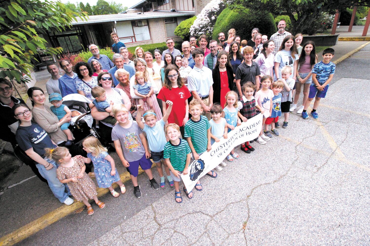 WITH A COMMON GOAL: Founders, board members, future students and their parts of Chesterton Academy of Our Lady of Hope gather outside the former St. Francis of Assisi Church and School in Warwick that the academy acquired on May 31 from the Diocese of Providence. (Cranston Herald photos)