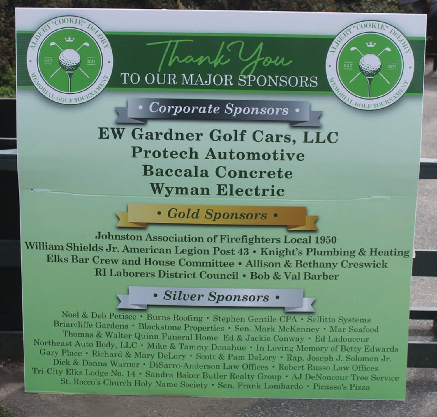 SUPER SPECIAL SIGN: Richard DeLory, Carol DeLory and Scott DeLory stand behind a sponsor’s board that was produced by Meaghen Foster of famed Bori Graphics of Cranston and listed all of the generous sponsors for Friday’s 3rd Annual Albert “Cookie” Memorial Golf Tournament. (Warwick Beacon photo by Alex Sponseller)