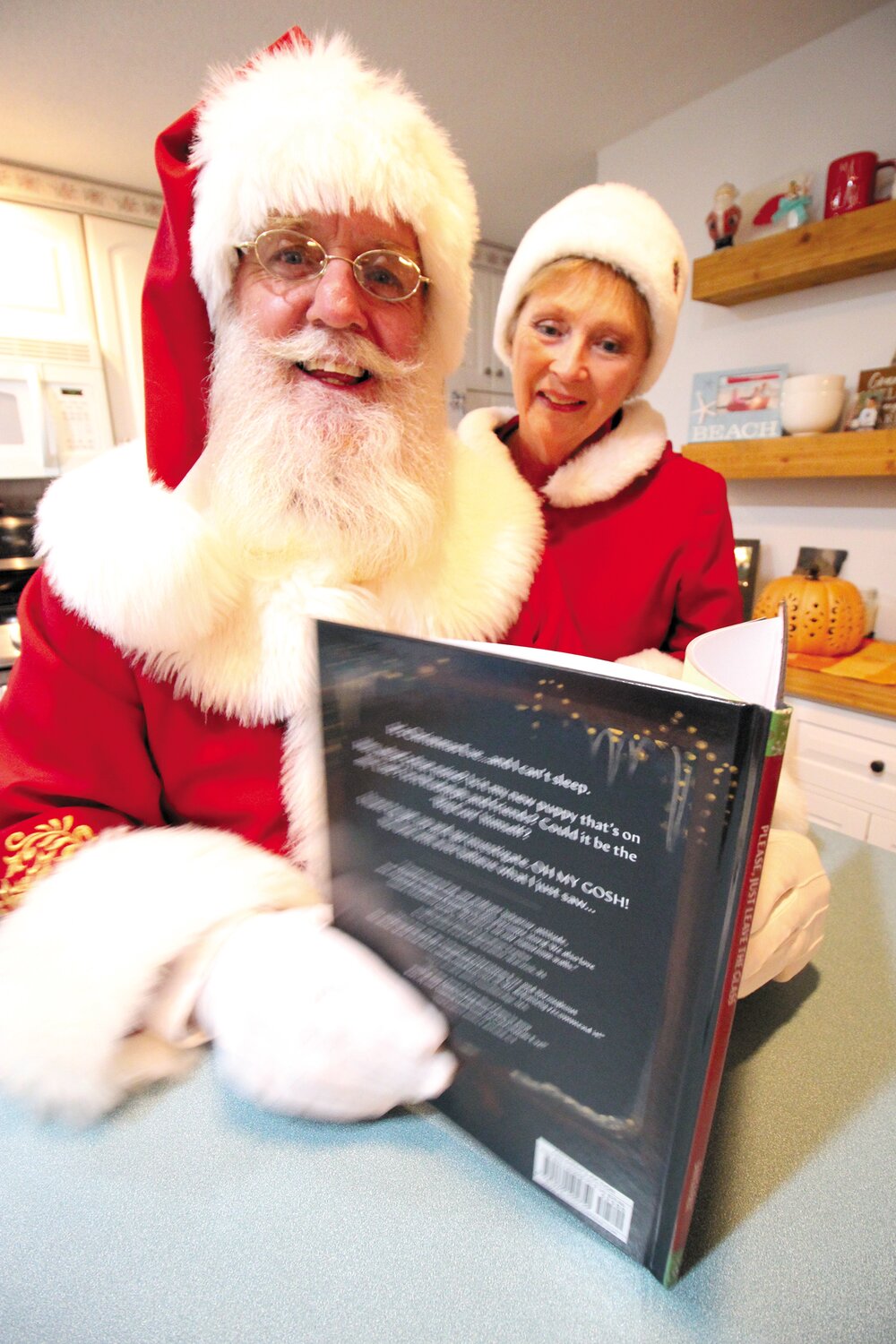 BOOKING ON SANTA:  Santa (Paul Evans) and Mrs. Claus (Peggy)  look over Santa’s recently published book to be a highlight at an event this Sunday at the K of C Hall on Sandy Lane. (Warwick Beacon photo)