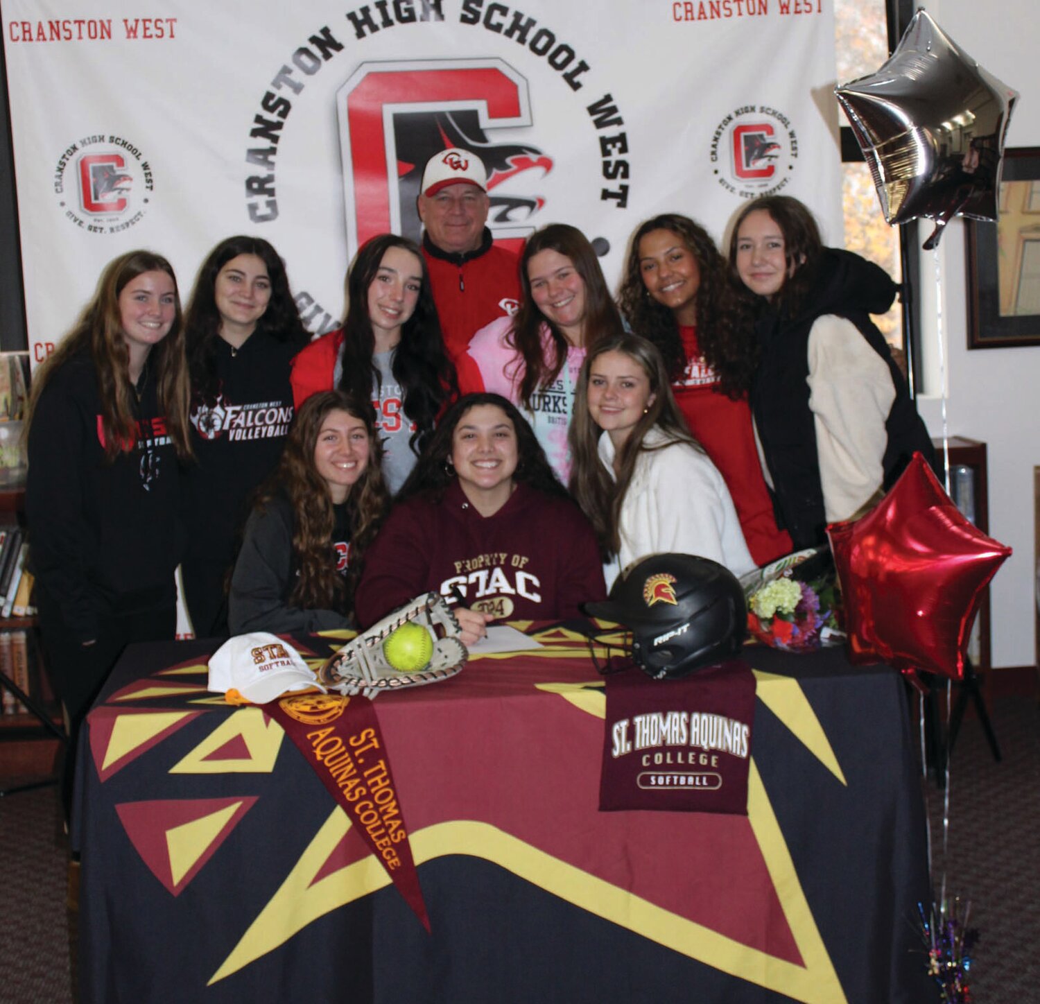 FALCONS FLY TOGETHER: Cranston West softball player Sofia Marella is joined by teammates as she signs her National Letter of Intent at a recent ceremony at the school. (Photos courtesy of CPSED)